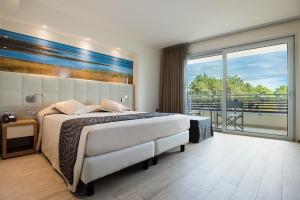 um quarto com uma cama grande e uma varanda em Laguna Park Hotel 4Superior em Bibione