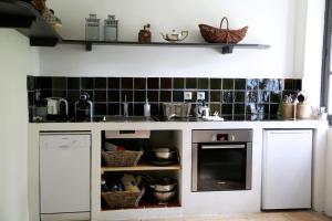 a kitchen with white cabinets and black tiles at La Suite de la Bastide in Val-de-Dagne