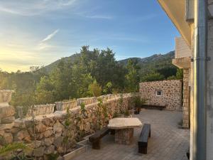 a stone wall with a bench on a patio at Bajic Apartmani in Seline