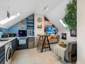 a kitchen and living room with blue walls at Upbeat Jungle Loft Apartment in Derby +32 photos