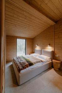 a large bed in a wooden room with a window at УЛІС Віняви in Derevach