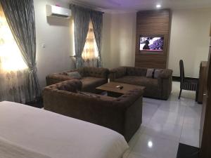 a living room with two couches and a tv at ADJ Royalty Hotel & Suites in Benin City