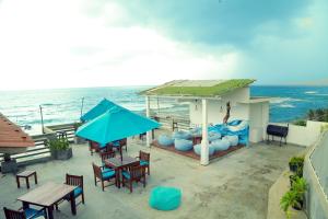 a patio with tables and chairs and a blue umbrella at Cozy Cocos Midigama in Ahangama