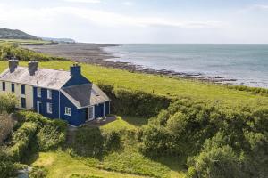 an aerial view of a house on a hill next to the ocean at Manteg - quaint holiday cottage by the sea with direct beach access in Aber-Arth