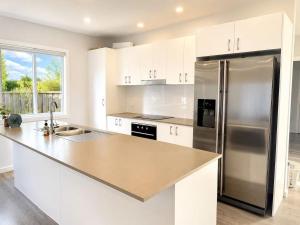 a kitchen with white cabinets and a stainless steel refrigerator at 22 Pimpama Home in Pimpama
