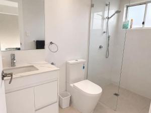 a white bathroom with a toilet and a shower at 22 Pimpama Home in Pimpama +9 photos