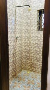 a bathroom with a shower with a tiled floor at AB Home Suites in Asofa +7 photos
