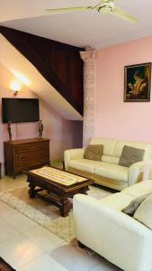a living room with white furniture and a flat screen tv at AB Home Suites in Asofa