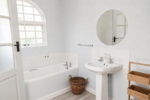 a bathroom with a tub and a sink and a mirror at Idylla Guest Home in Kenton on Sea +27 photos