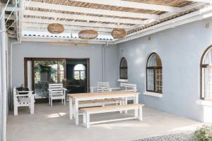 a patio with white chairs and a wooden table at Idylla Guest Home in Kenton on Sea