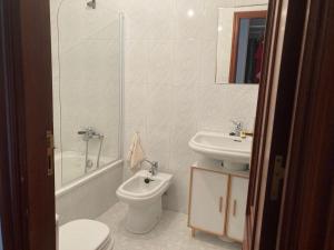 a bathroom with a toilet and a sink and a shower at Refugio Mar de Boiro in Boiro +3 photos