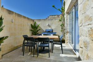 an outdoor patio with a wooden table and chairs at Xewkija Ta' L-Ghagin in Xewkija