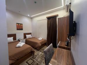 ein Hotelzimmer mit zwei Betten und einem Flachbildfernseher in der Unterkunft Central Cairo Hotel in Kairo