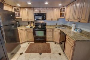 a kitchen with wooden cabinets and a stainless steel refrigerator at Wild Irishman 1059 by SummitCove Lodging in Colorado in Keystone