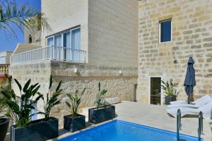 a villa with a swimming pool and a house at Xewkija Ta' L-Ghagin in Xewkija