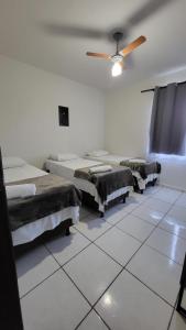 a room with three beds and a ceiling fan at Golden Silver UNIQUE in Curvelo