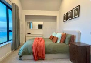 a bedroom with a bed with an orange blanket on it at Kelsingra Self Catering in Lerwick/Tingwall Airport