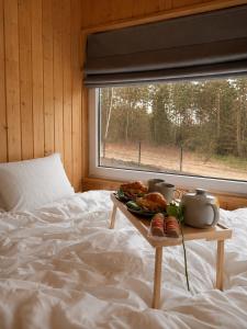 a tray of food on a bed next to a window at Domek BrzozoweLove in Szczodrowo
