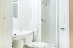a white bathroom with a sink and a toilet at Avonmore Hotel in London +15 photos