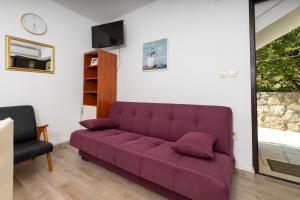 a purple couch in a living room with a clock at Apartments with parking space Zavala, Hvar - 8710 in Jelsa