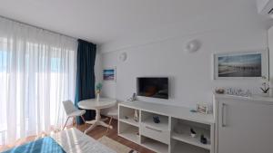 a white bedroom with a desk and a table at Cozy Studio Olimp in Olimp