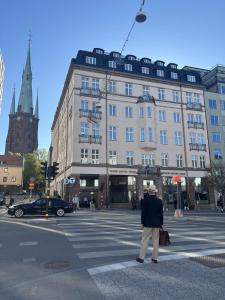 a man crossing a street in front of a building at Thon Hotel Vasa in Stockholm