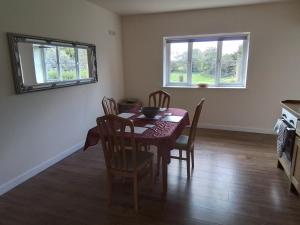 a dining room with a table and chairs and two windows at Elderflower Cottage in Stamford