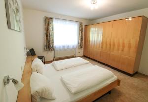 a bedroom with a large white bed and a window at Hotel Garni Tirol in Walchsee +59 photos