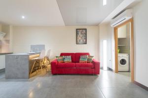 a living room with a red couch and a kitchen at Suites Garden Loft Velázquez in Las Palmas de Gran Canaria