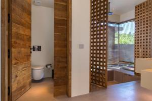 a bathroom with a toilet and a wooden door at Klay Hotel Faralya Adults Only in Faralya +36 photos