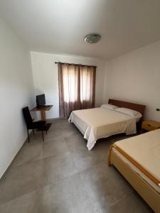 a bedroom with two beds and a desk and a window at L'imbarco ROOMS in Badolato Stazione
