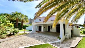 a house with a palm tree in front of it at Villa Oasis by Cleverdetails private pool, walk distance in Vilamoura