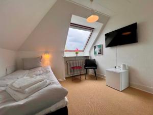 ein Schlafzimmer mit Bett, Fernseher und Fenster in der Unterkunft Sverres Hotel in Rønne