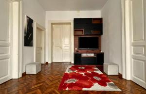 a living room with a television and a red rug at Fuchsl Palace Grand Suite - Ultra Central in Oradea