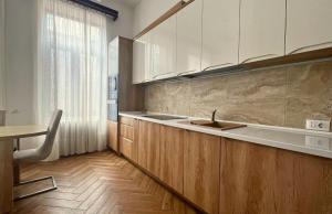 a kitchen with wooden cabinets and a sink and a table at Fuchsl Palace Grand Suite - Ultra Central in Oradea