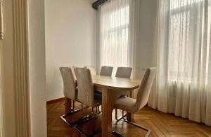a dining room with a wooden table and chairs at Fuchsl Palace Grand Suite - Ultra Central in Oradea