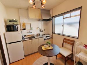 a small kitchen with a table and a refrigerator at DiDi Sakura 205 in Tokushima