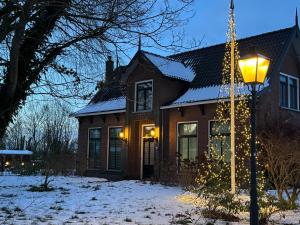 a house with christmas lights in the snow at B&B Pastorie Jelsum in Jelsum +10 photos
