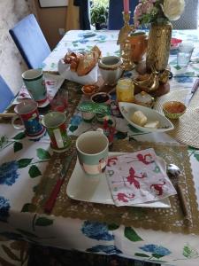 a table with cups and plates of food on it at chambre chez hote familiale 2, 4, 5,6 in Mareuil-sur-Lay