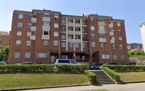 a large brick building with cars parked in front of it at Castros Homes in Santander