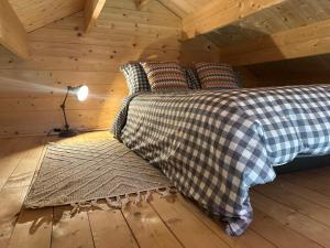 a bed in a wooden cabin with a lamp at Greenwood Chalet in Ottershaw