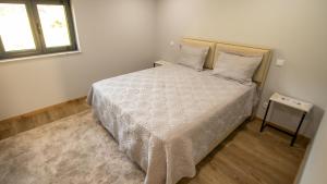 a bedroom with a bed with a white comforter and a window at Casa da Moura - Arcos de Valdevez in Arcos de Valdevez
