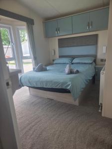 a bedroom with a large bed with blue sheets and pillows at JLUX Lodges in Crowle