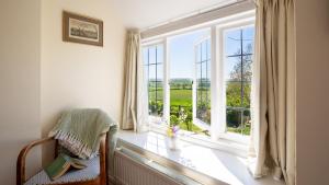 a room with a window with a chair and a window view at Priors Mead Cottage in Claydon