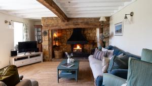 a living room with a couch and a fireplace at Priors Mead Cottage in Claydon