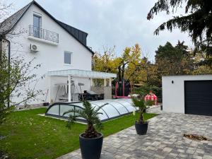 a white house with a patio with two palm trees at Pool & Chill Balaton in Balatonvilágos