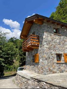 a stone building with a wooden balcony on it at Baita dell'Est in Mese