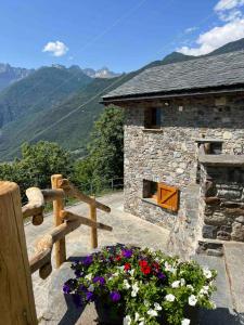 a stone building with flowers in front of it at Baita dell'Est in Mese +16 photos