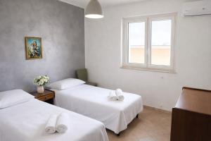 two beds in a room with a window at WHITE COAST APARTMENTS - Family Stays and Free Parking in Realmonte +10 photos