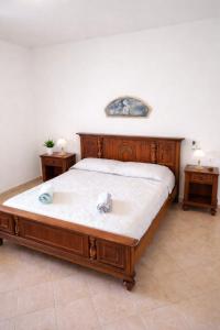 a bedroom with a wooden bed with two night stands at WHITE COAST APARTMENTS - Family Stays and Free Parking in Realmonte
